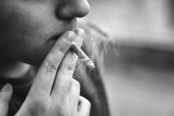 Um tipo fuma um cigarro lá fora, retrato, close-up — Fotografia de Stock