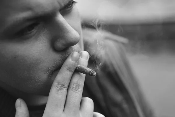 Um tipo fuma um cigarro lá fora, retrato, close-up — Fotografia de Stock