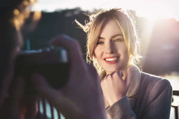 Ein Mann porträtiert eine glücklich lächelnde Frau, die an sonnigen Sommer- oder Frühlingstagen im Freien auf der Brücke steht — Stockfoto