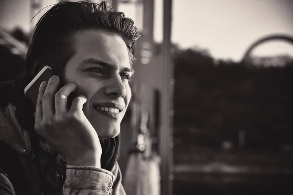 Lindo chico sonriente hablando por teléfono parado en la novia. Primer plano retrato — Foto de Stock