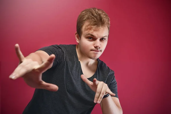 Jonge stijlvolle pathos Tiener jongen draagt grijs t-shirt over geïsoleerde roze achtergrond doen rock symbool met de handen omhoog. Muziekster. Teken maar. koel teken — Stockfoto