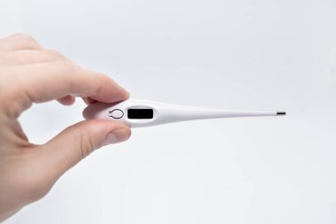 Beyaz arkaplanda beyaz düğmeli dijital termometre tutan adam