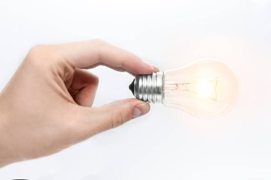 Beyaz arka planda yanan bir ampulü tutan bir adam.