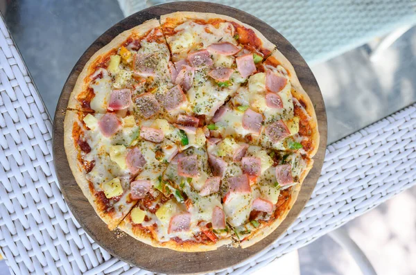 Hawaiian Pizza. Pizza topped up with pineapple, ham, onions, cheese, tomatoes, bacon,Bell pepper and sauce.  top view
