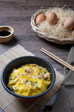 Tavuk, soğan ve özel sosla pişirilmiş yumurta ile kaplı Oyako-don pirinç kasesi. Oyakodonburi Japon yemekleri ahşap arka planda.