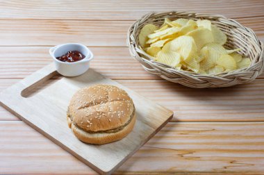 Ketçaplı, az yağlı hamburger ve patates cipsi. Yemeye hazır..