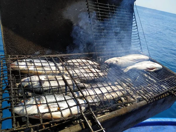 Grilled fish on a background of blue sea. Fresh fish from the Mediterranean. Fishing off the coast of Rhodes