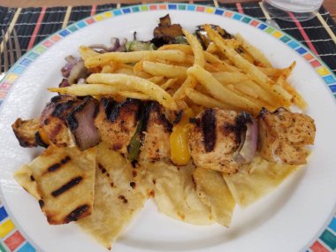 Lezzetli kebap ve meze ile tabak. Hellas 'ın geleneksel mutfağı. Rodos adasının kıyısında atıştırmalık bir şeyler. Et yemeği. Tavuk ve domuz eti lezzetleri ve garnitür.