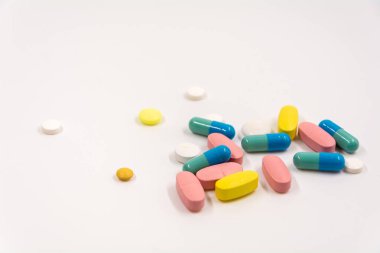 çok renkli tabletler ve kapsüller beyaz arkaplanda yatar
