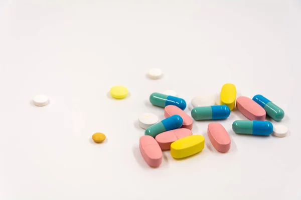 çok renkli tabletler ve kapsüller beyaz arkaplanda yatar