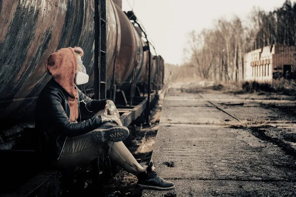 Paslı tankların arkasında kızıl saçlı ve gaz maskeli bir kız..