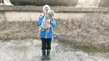 12-13 yaşındaki mavi ceketli bir çocuk peluş bir kediyle oynuyor. Yavaş çekim