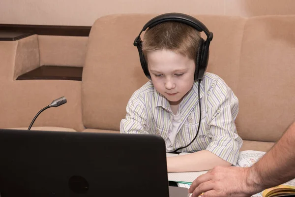 a 7 year-old watches an e-learning video with a teacher on a computer in the living room of the house. E-learning, online education and online social distancing protection from COVID-19