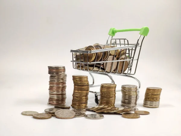 Mini boodschappenmandje met munten naast de stapels munten. Financiën en het concept van het besparen van geld. — Stockfoto