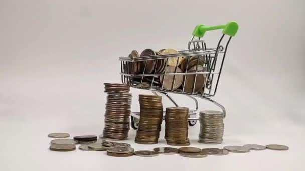 Na Mini nákupní košík s mincemi padají z vrcholu peněz a vedle hromad mincí. Finance a koncept úspory peněz — Stock video