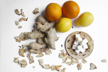 Meyve. Zencefilli portakallı limon ve ahşap bir tabakta şeker parçaları, hepsi beyaz arka planda..