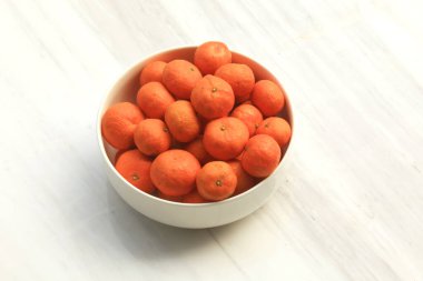 Mandalina portakalları mermer tezgahın üstünde beyaz kasede sergilenir.