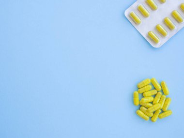 Tedavi için ilaç reçetesi. İlaç yeşil ve sarı haplar veya mavi arka planda fotokopi alanı olan kapsüller. İlaç, sağlık için konteynırda tedavi. Antibiyotik