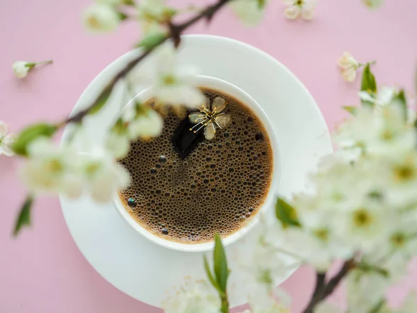 Tazza bianca di caffè e fiori di fiori primaverili sul tavolo rosa. Buongiorno romantico americano. Caffè e bar, concetto di arte barista. Vista dall'alto. Posa piatta — Foto Stock