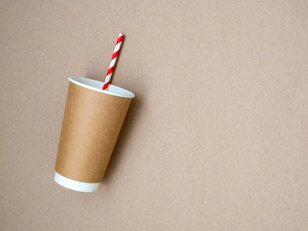 Afhaalkoffiemok met papieren wit en rood drinkstro op ambachtelijke papieren ondergrond. Het concept van een wereld zonder plastic en een schone planeet. Ruimte voor tekst. Geen verspilling. Vlakke lay, bovenaanzicht — Stockfoto