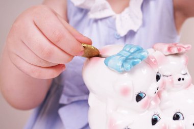 Bir çocuk kumbaraya para koyuyor. Kız para biriktiriyor. Domuz kumbarası