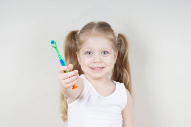 Avrupalı görünümlü küçük bir kız arka planda dişlerini fırçalıyor. Sağlıklı diş kavramı. Dişçilik