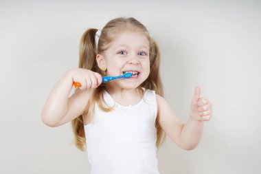 Avrupalı görünümlü küçük bir kız arka planda dişlerini fırçalıyor. Sağlıklı diş kavramı. Dişçilik