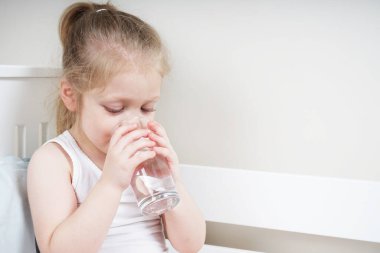 Ateşi olan küçük kız hasta ve su içiyor. Hastalık izninde evde..