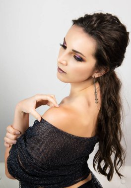 Güçlü makyajlı güzel bir kadın yana bakıyor.