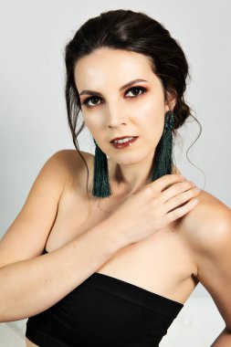 Güçlü makyajlı ve yeşil küpeli güzel bir kadın.