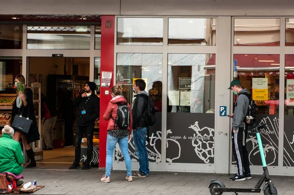 COLOGNE, ALMANE 2 Mayıs 2020: Müşteriler mağazada kuyrukta bekliyor, sosyal uzaklık 