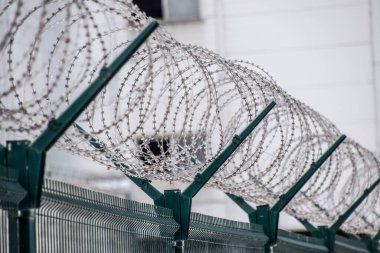 Swirls of barbed wire over the fence. The fence symbolizes prison, non-freedom, totalitarianism and prohibitions. clipart