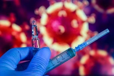 Coronavirus aşısı. Tıbbi eldivenlerdeki bir el, aşıyı ve şırıngayı koronavirüsün arka planına karşı tutar. covid-19,