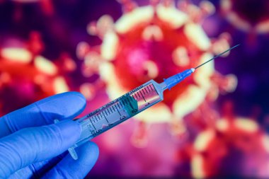 Coronavirus aşısı. Tıbbi eldivenlerdeki bir el, aşıyı ve şırıngayı koronavirüsün arka planına karşı tutar. covid-19,