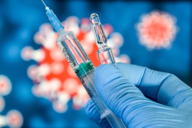 Coronavirus aşısı. Tıbbi eldivenlerdeki bir el, aşıyı ve şırıngayı koronavirüsün arka planına karşı tutar. covid-19,