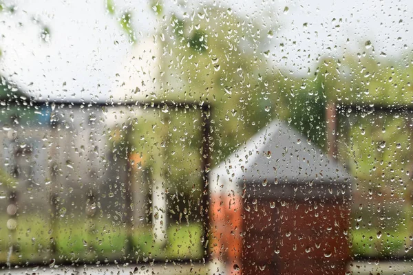 Raindrops on the window pane. Blurred background outside the window in the rain.