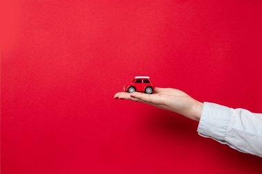 Mutlu Noeller ve mutlu bayramlar kartı ya da internet afişi. Mavi gömlekli bir kadın, kırmızı arka planda kırmızı bir araba mankeni tutuyor.