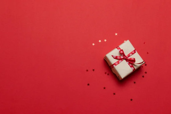 Gratulációs kártya ajándékdobozzal vagy ajándékdobozzal, konfetti a piros asztalon. Flat lay kompozíció születésnapra, anyák napjára, boldog karácsonyt és új évet — Stock Fotó
