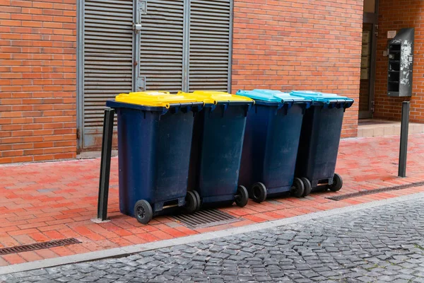 Различные пластиковые контейнеры для мусора с цветными крышками для экологически чистой сортировки мусора для переработки с полными пластиковыми пакетами — стоковое фото