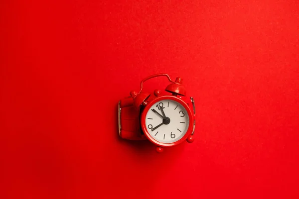 Concept créatif de Noël de réveil rouge horloge ronde sur un modèle de voiture jouet sur un fond rouge, vue de dessus . — Photo