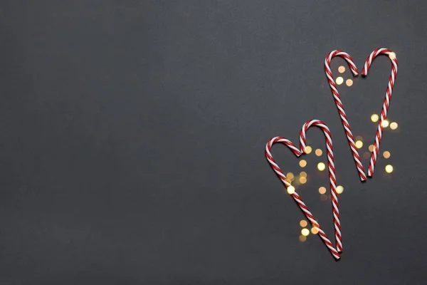 Veselé svátky blahopřání s cukrovou třtinou ve tvaru srdce s třpytkou na tmavém pozadí. Narozeniny, Valentýn, Vánoce, Nový rok. Plochý styl — Stock fotografie