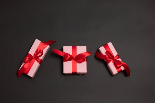 Un montón de grandes regalos sorpresa envueltos con lazo de cinta roja sobre un fondo oscuro . — Foto de Stock