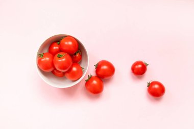 Pembe arka plandaki kasede taze kırmızı domatesler.