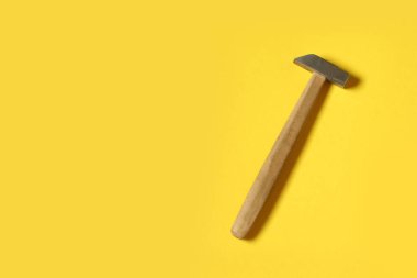 Sarı zemin üzerinde küçük metal çekiç ve metin için yer.