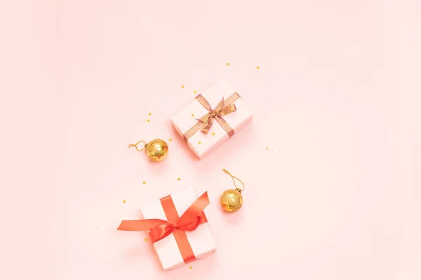 Composición decorativa de Navidad con caja de regalo de papel, bolas de oro y lazo de cinta de oro sobre un fondo rosa. Piso laico, vista superior para las compras de vacaciones en el día de boxeo — Foto de Stock