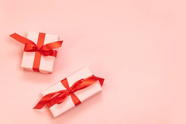 Pembe arka planda kırmızı fiyonklu güzel hediye kutularının olduğu düz bir yer. Doğum günü, Sevgililer Günü, Noel, Yeni Yıl. Düzleştirme biçimi
