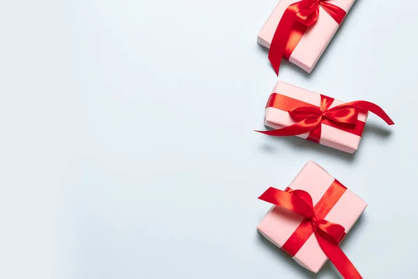 Composición plana con cajas de color rosa con cintas de satén rojo sobre un fondo azul para cumpleaños, día de la madre, feliz Navidad y año nuevo —  Fotos de Stock