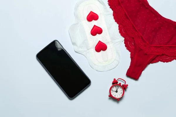 Weibliche Spitze rote Höschen mit medizinischen weiblichen schlanken Baumwolle Menstruationsunterlage, Liebesform, Smartphone auf blauem Hintergrund. — Stockfoto