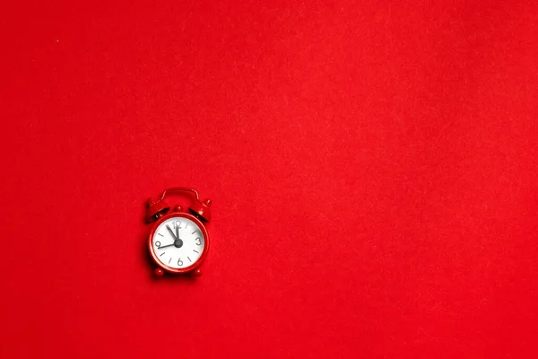 Rode wekker in een minimale stijl op een rode achtergrond. Plat gelegd. Vakantie concept — Stockfoto