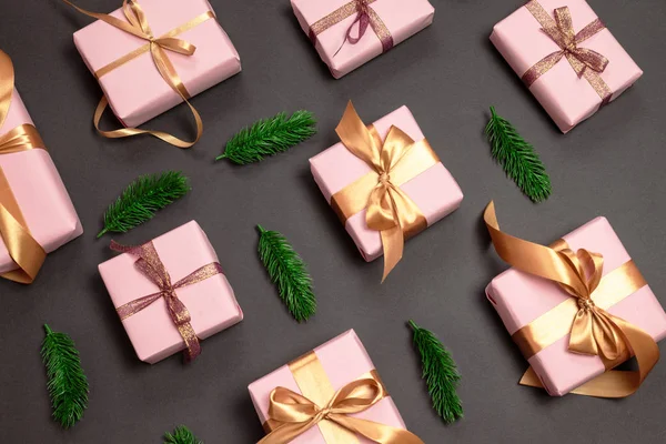 Üdülési minta válogatott ajándékok csomagolva rózsaszín gondolat egy arany napellenző és zöld fenyő sprigs sötét háttérrel. Felülnézet fénymásoló felülettel. Lapos feküdt kreatív ötlet design — Stock Fotó